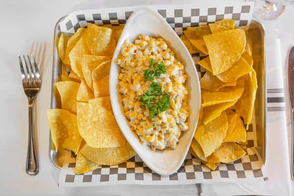 creamy street corn dip with tortilla chips served in a basket-style appetizer tray