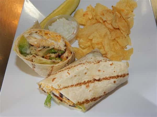 grilled chicken wrap with cheese and avocado with a side of chips, coleslaw and a pickle spear