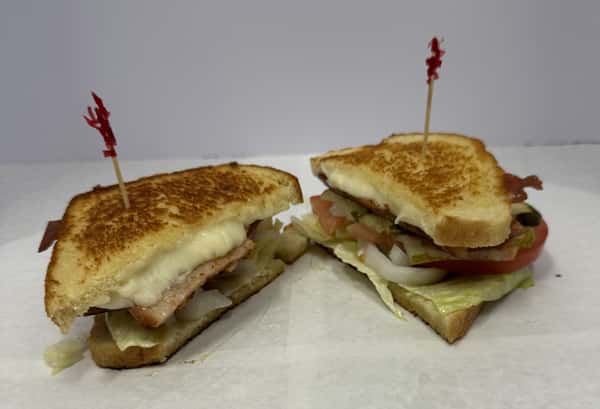 Grilled sandwich with cheese, bacon, lettuce, tomato, onions, and pickles, secured with toothpicks.