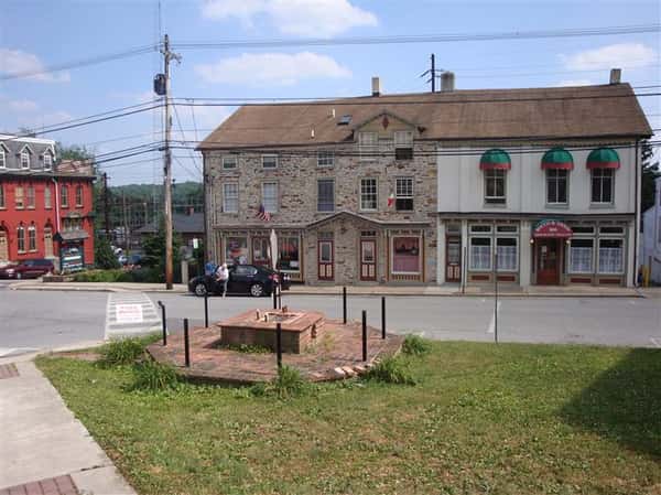 exterior brick building of rocco & anna's ristorante italiano near a street with a small monument across the street