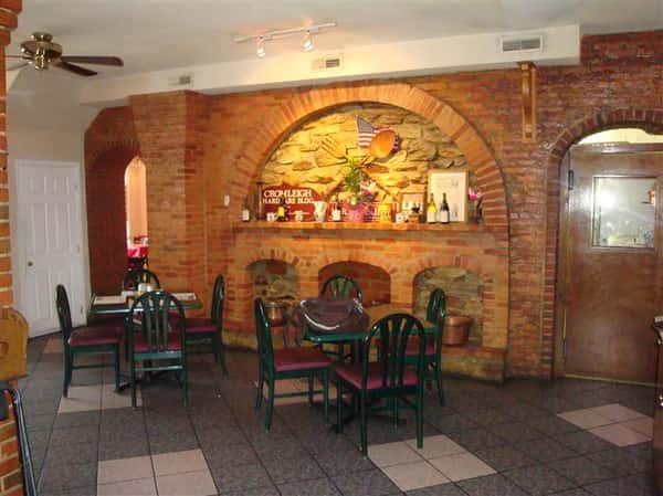 interior dining area with tables and chairs with a brick wall covered with decorations