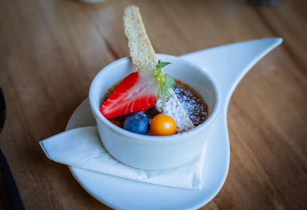 A dessert in a cup with fruit and powdered sugar