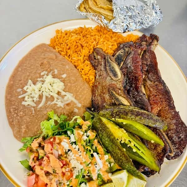 Grilled top sirloin with refried beans, guacamole, and a side of cactus salad on a white plate