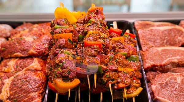 Marinated meat skewers coated with Indian spices and fresh herbs, prepared ready for grilling.