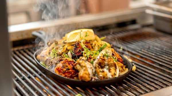 Sizzling grilled meat platter with charred vegetables, fresh herbs, lemon and aromatic Indian spices.