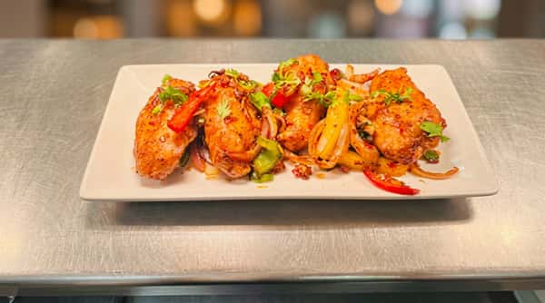 Crispy fried fish pieces served with colourful peppers, onions, fresh herbs and a vibrant spiced coating.