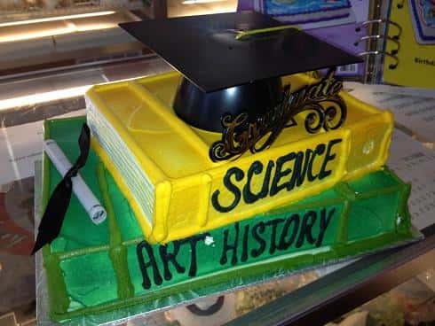 graduation cake shaped like edible books and gradiation cap