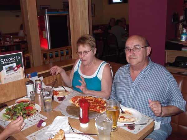 People having pizza and drinks at the table and posing for photo
