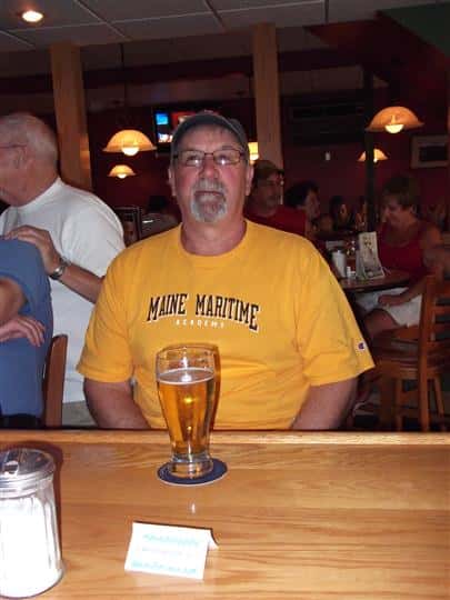 Man posing for photo with a glass of beer at the bar