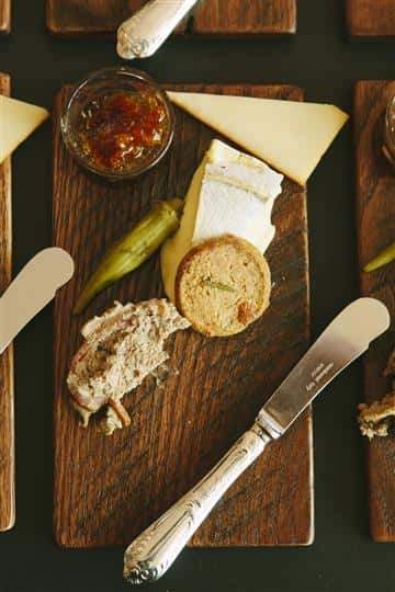 a mini piece of bread with a slide of cheese, side of dip and a pepper
