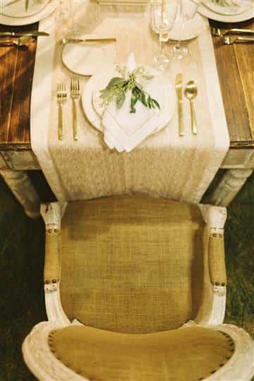 closeup of gold chair with place setting with leaves on top of napkin