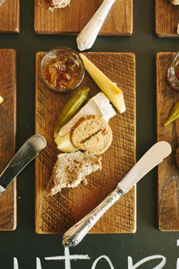 a mini piece of bread with a slide of cheese, side of dip and a pepper