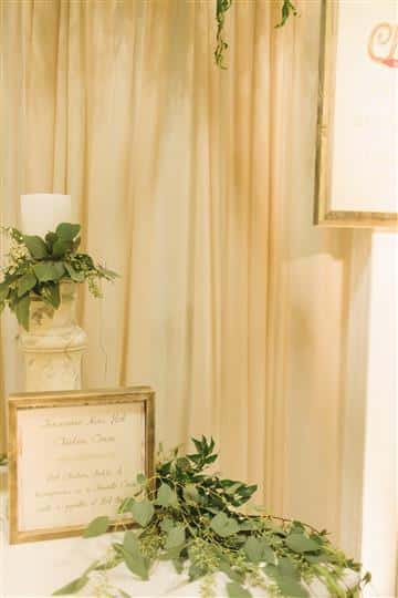 a sign in front of a white candle with green leaves