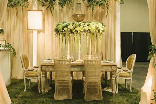 the white table with six chairs around with white floral centerpiece with vines hanging