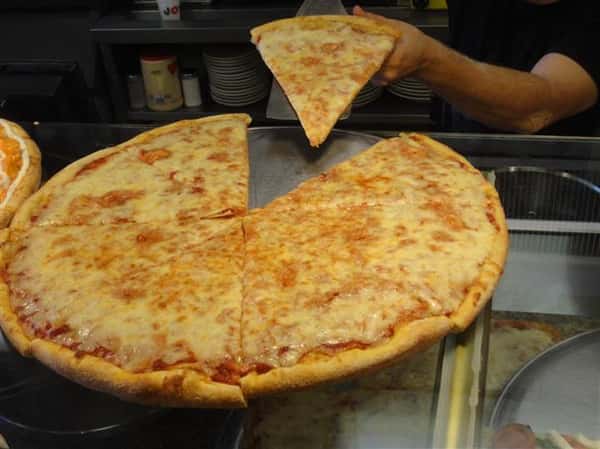 large cheese pizza with a person taking a slice