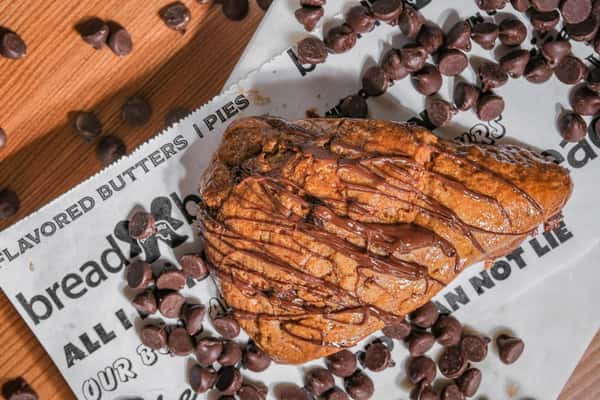 Triple chocolate scone drizzled with chocolate and topped with chocolate chips, freshly baked at Bread and Butter Bakery.