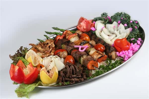 assortment of grilled meat on a tray with veggies and garnish