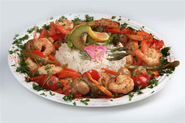 a bed of rice topped with garnish with grilled shrimp and vegetables