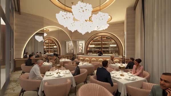 Grand restaurant entrance hallway featuring illuminated wine displays, chandeliers, and a luxurious dining atmosphere.