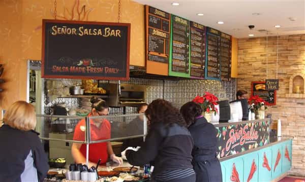 Salad bar counter with staff serving people