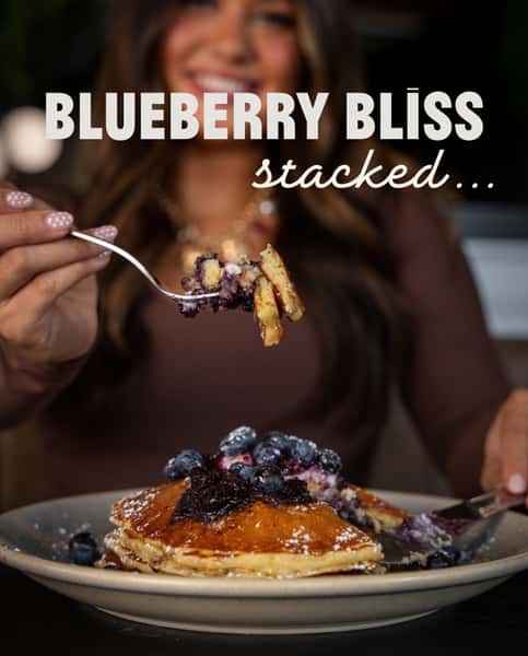 A stack worth savoring. Three fluffy pancakes with fresh blueberries, topped with house-made lemon ricotta and blueberry compote, then served with warm 100% pure maple syrup. Sweet, bright, and made for brunch at eggspectation.