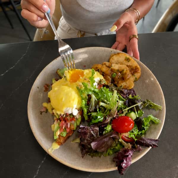 Brunch plate with eggs Benedict, fresh greens, avocado, and roasted potatoes