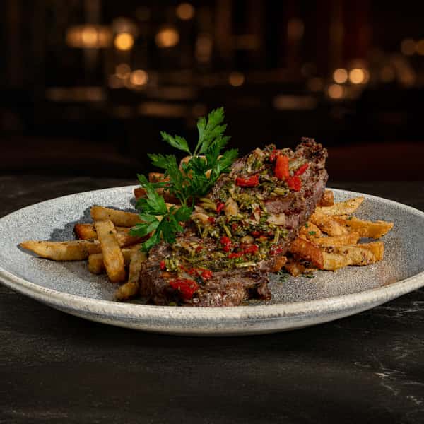 Grilled steak served over crispy fries and topped with fresh herbs and peppers
