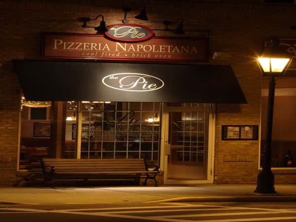 exterior of store front at night with sign reading the pie pizzeria napoletana coal fired brick oven