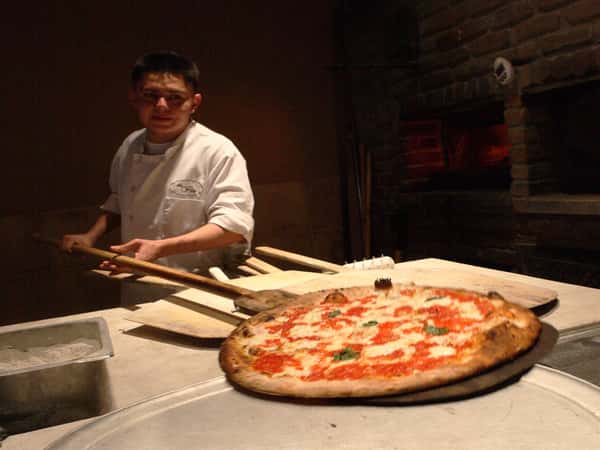 employee moving pizza to a large pan