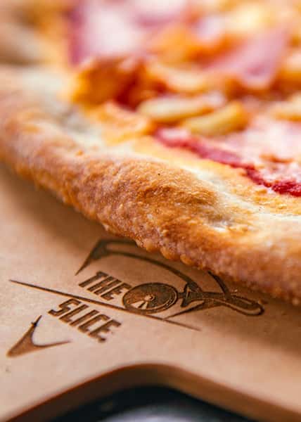 close up of pizza slice and branded pizza board