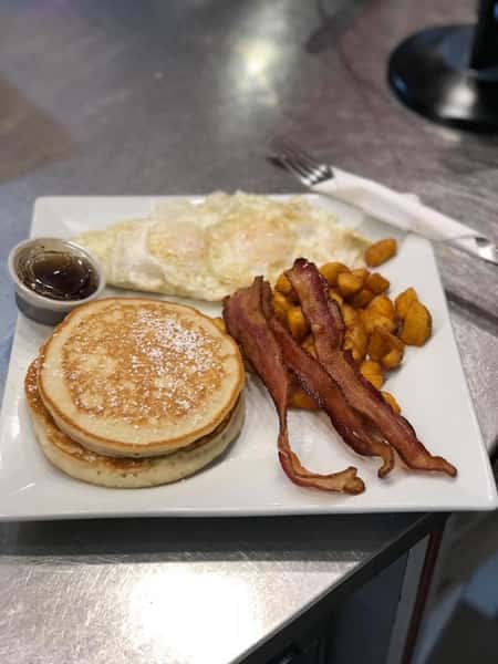 Pancakes, eggs, home fries, and bacon on a plate
