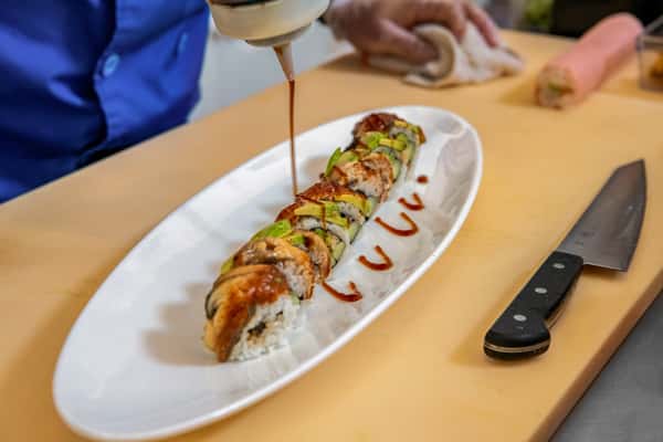drizzling eel sauce on the sushi roll