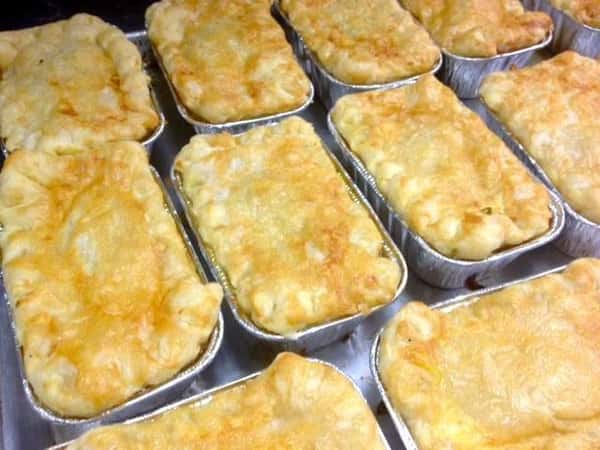 Baked casseroles in trays lined up in rows on a table