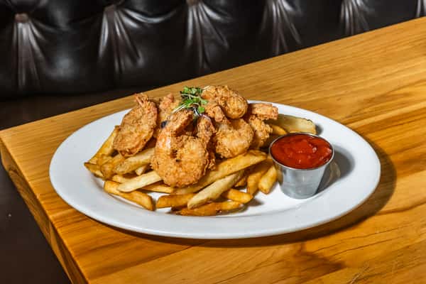 Golden fried shrimp piled over thick-cut French fries, served with a side of ketchup and garnished with microgreens. A satisfying seafood platter with Southern flair and casual comfort appeal.