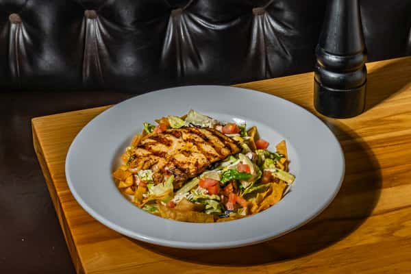 Grilled chicken salad with seasoned grilled chicken breast served over crisp lettuce, tomatoes, and tortilla strips. A hearty salad combining fresh greens with savory protein.