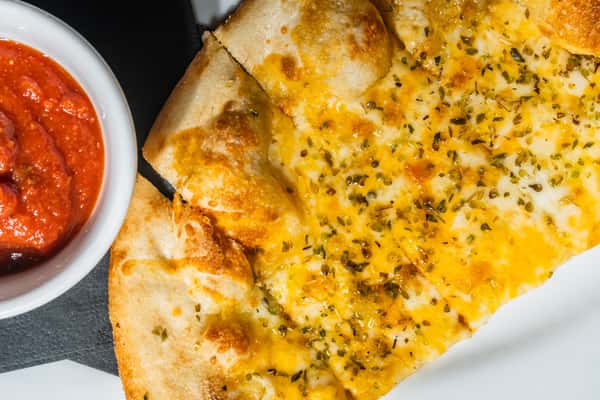 Cheesy garlic flatbread topped with herbs and served with a side of marinara dipping sauce. A flavorful starter or side dish ideal for sharing.