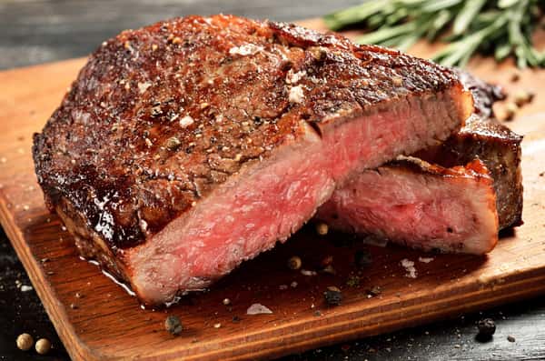 Sliced medium rare steak resting on a wooden cutting board