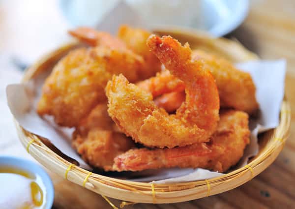 Basket of fried onion rings and fried bites served with dipping sauce