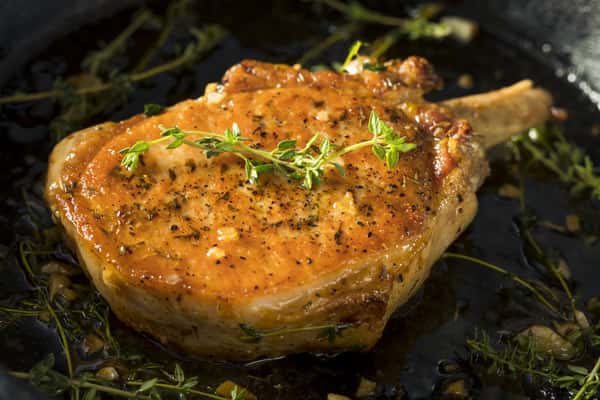 Baked chicken breast topped with a creamy orange sauce and herbs in a dark panv
