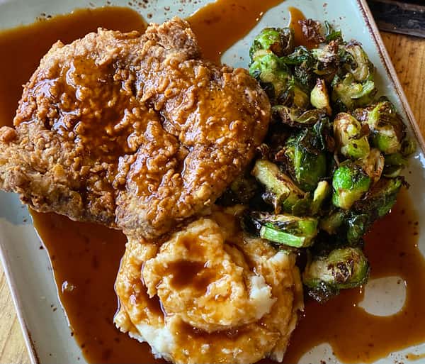 Fried chicken served with gravy and Brussels sprouts on a plate