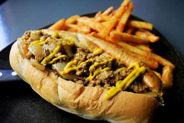 Cheesesteak style sandwich topped with peppers and served with fries