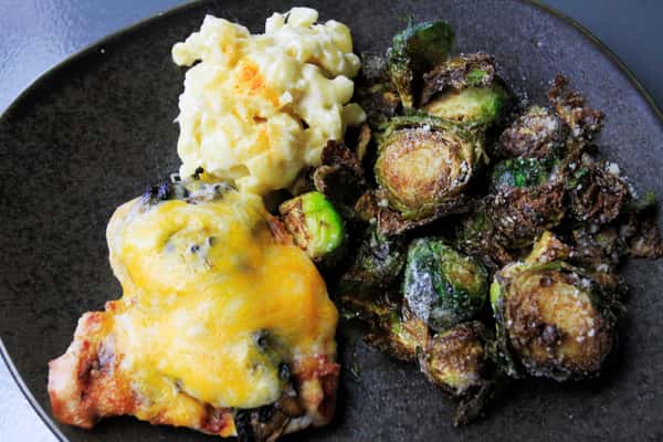 Plated entrée with Brussels sprouts and a cheesy baked casserole on a dark plate