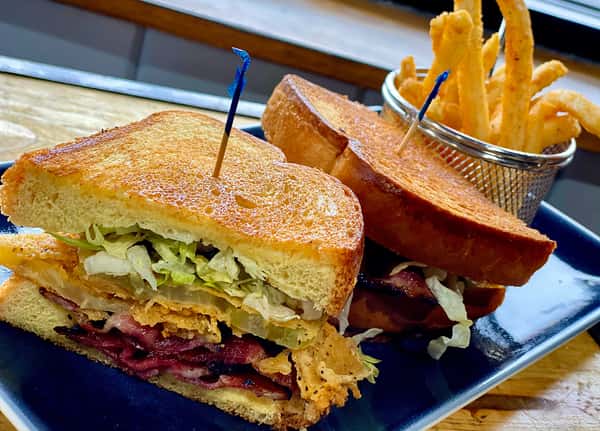 Reuben style sandwich on toasted bread served with fries and a side of coleslaw