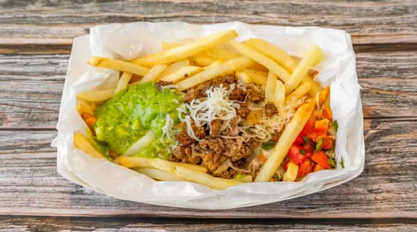 Loaded fries with ground meat, shredded cheese, guacamole, and pico de gallo in a paper-lined basket.