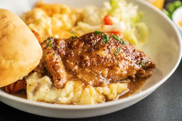 Savory chicken smothered in brown gravy over creamy mashed potatoes with a side of fresh salad.