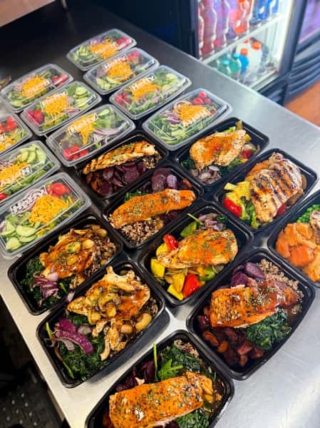 meal prep with fresh garden salads, grilled chicken, roasted vegetables, and grains packed in containers for healthy prepared meal service.