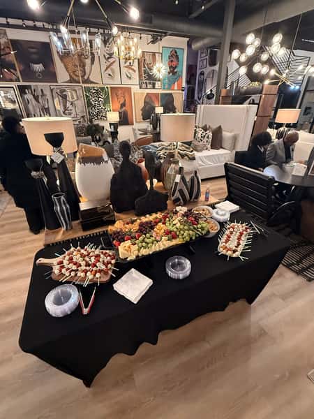 Luxury formal table setting with gold charger plates, patterned china, polished silverware, and white floral centerpiece on a black tablecloth and satin runner, styled for an upscale wedding or private dining event.