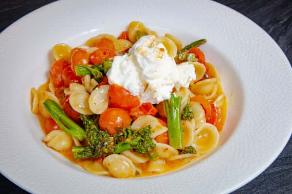 Creamy burrata served over house-made pasta with asparagus, cherry tomatoes, and rich tomato sauce at Dulivia Ristorante Italiano in Springdale, Utah.
