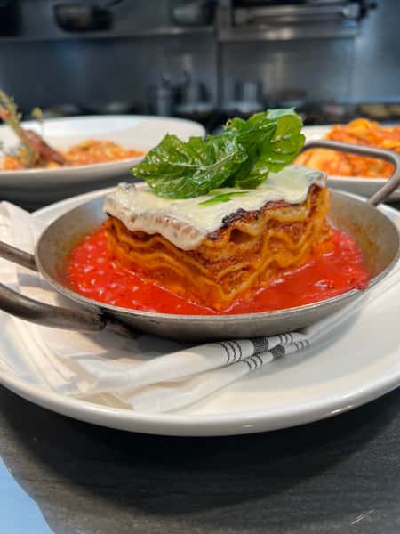 House-made lasagna topped with creamy burrata and fresh basil in rich tomato sauce at Dulivia Ristorante Italiano in Springdale, Utah.