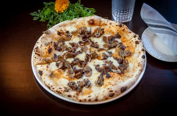 Stone-hearth mushroom pizza with melted mozzarella and fresh herbs at Dulivia Ristorante Italiano in Springdale, Utah.